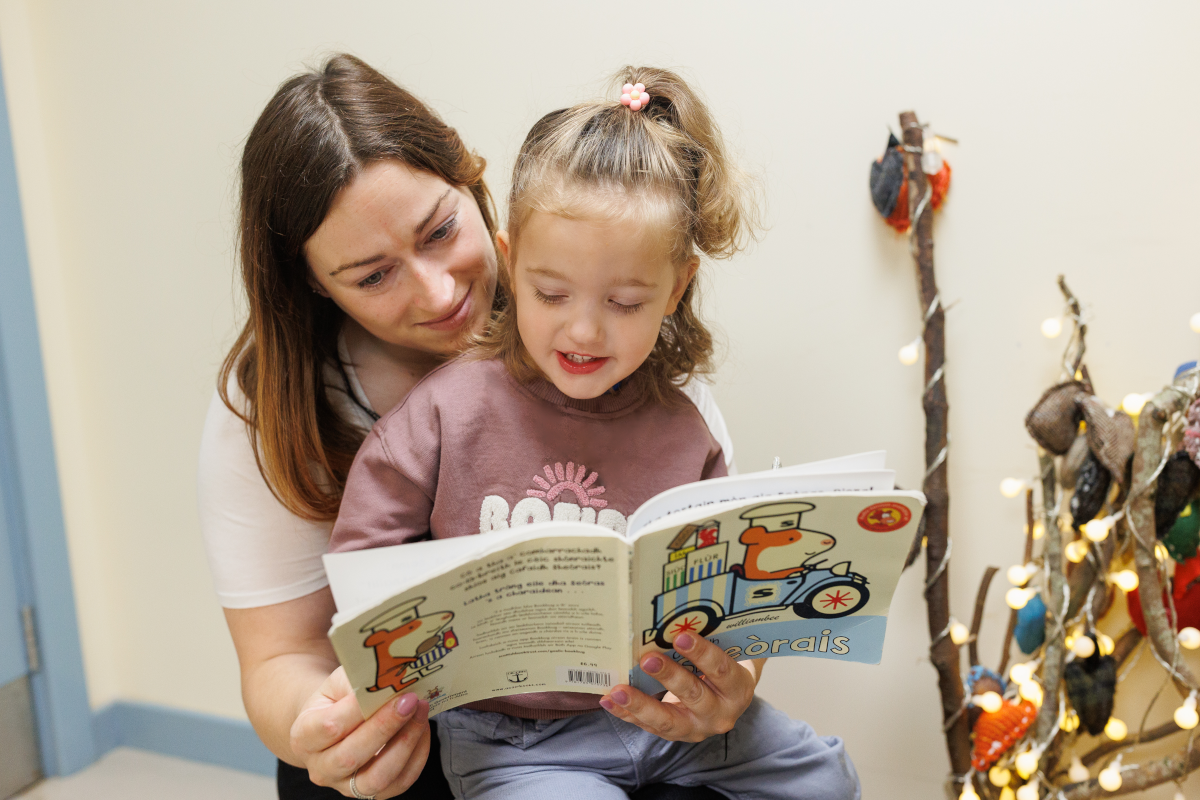 A woman with a child on her lap reading a book.