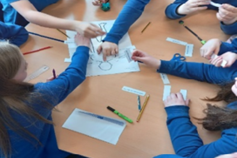 Pupils sat around a table completing an exercise on paper